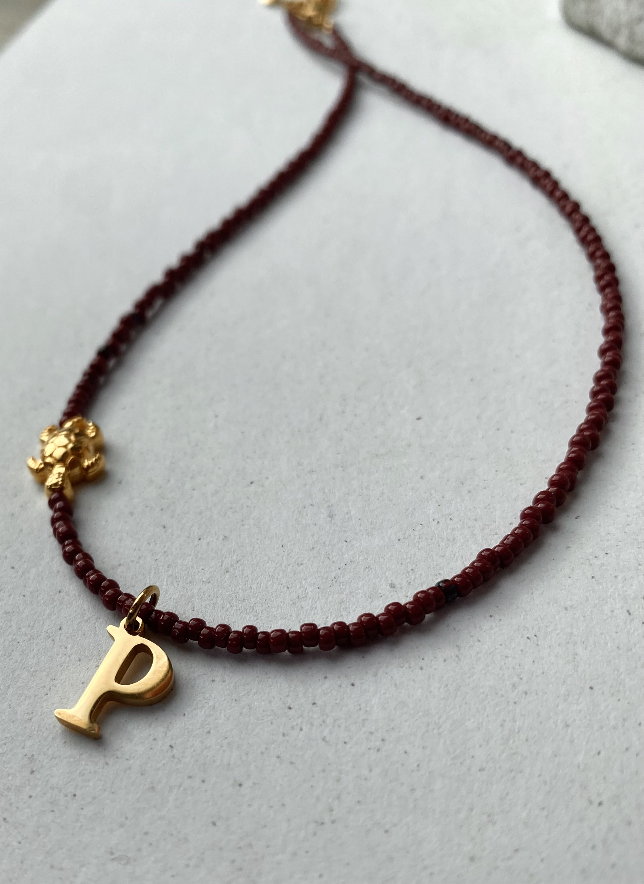 Bordeaux parelketting met schildpad-bedeltje en gouden beginletter
